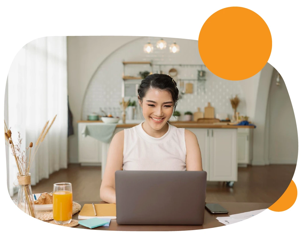 Una mujer sonriendo frente a su laptop trabajando desde casa.