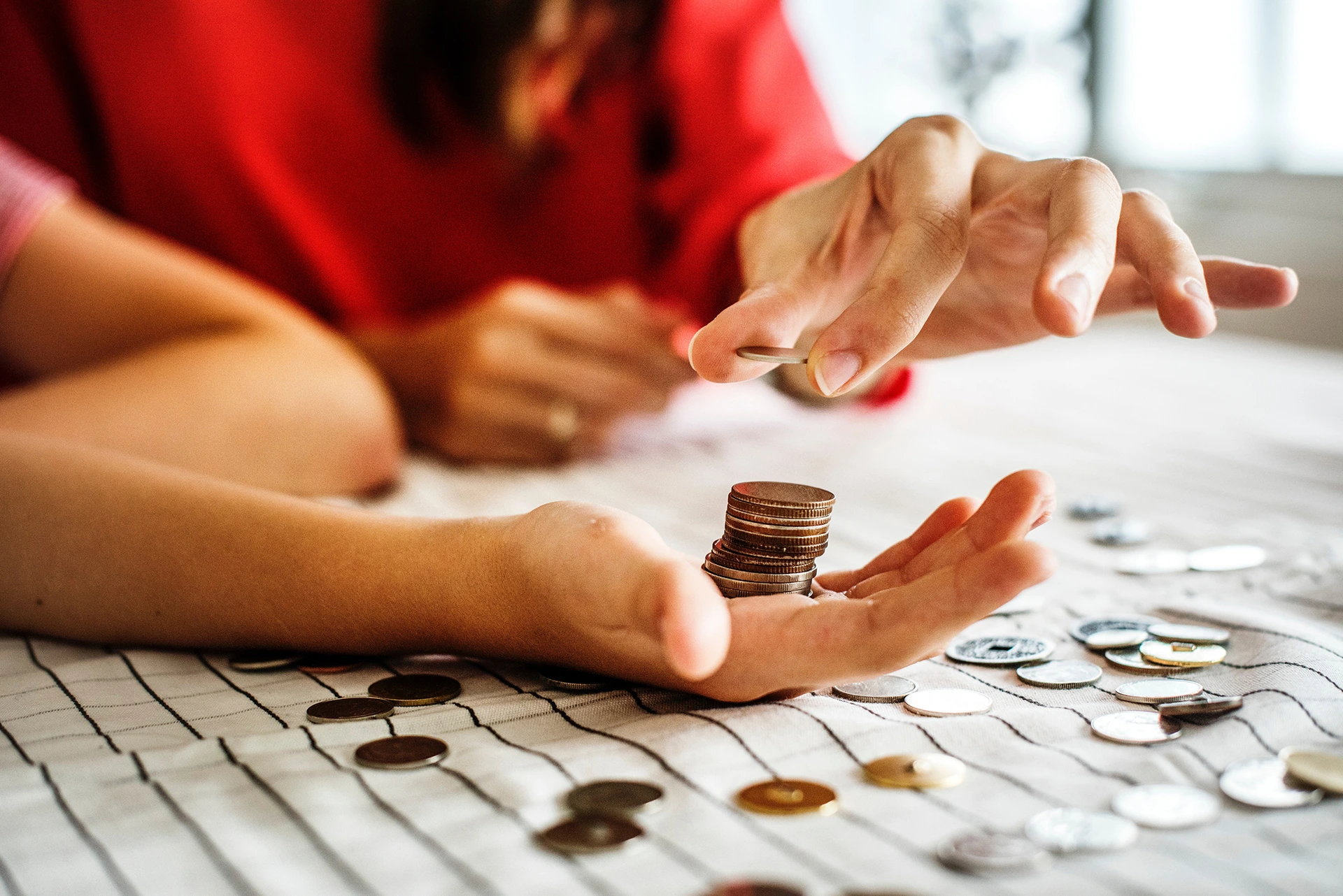 Mujer colocando monedas en la mano de una niña.